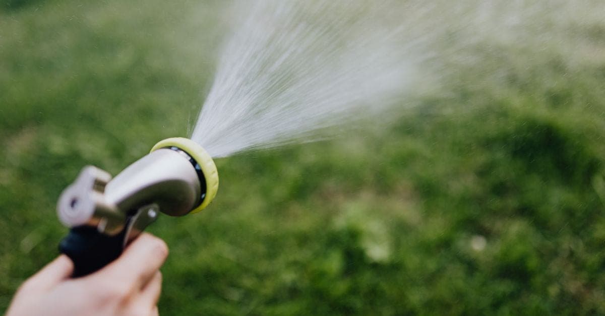 Blocked drain clearing — high-pressure jet clearing a blocked stormwater drain in a residential yard